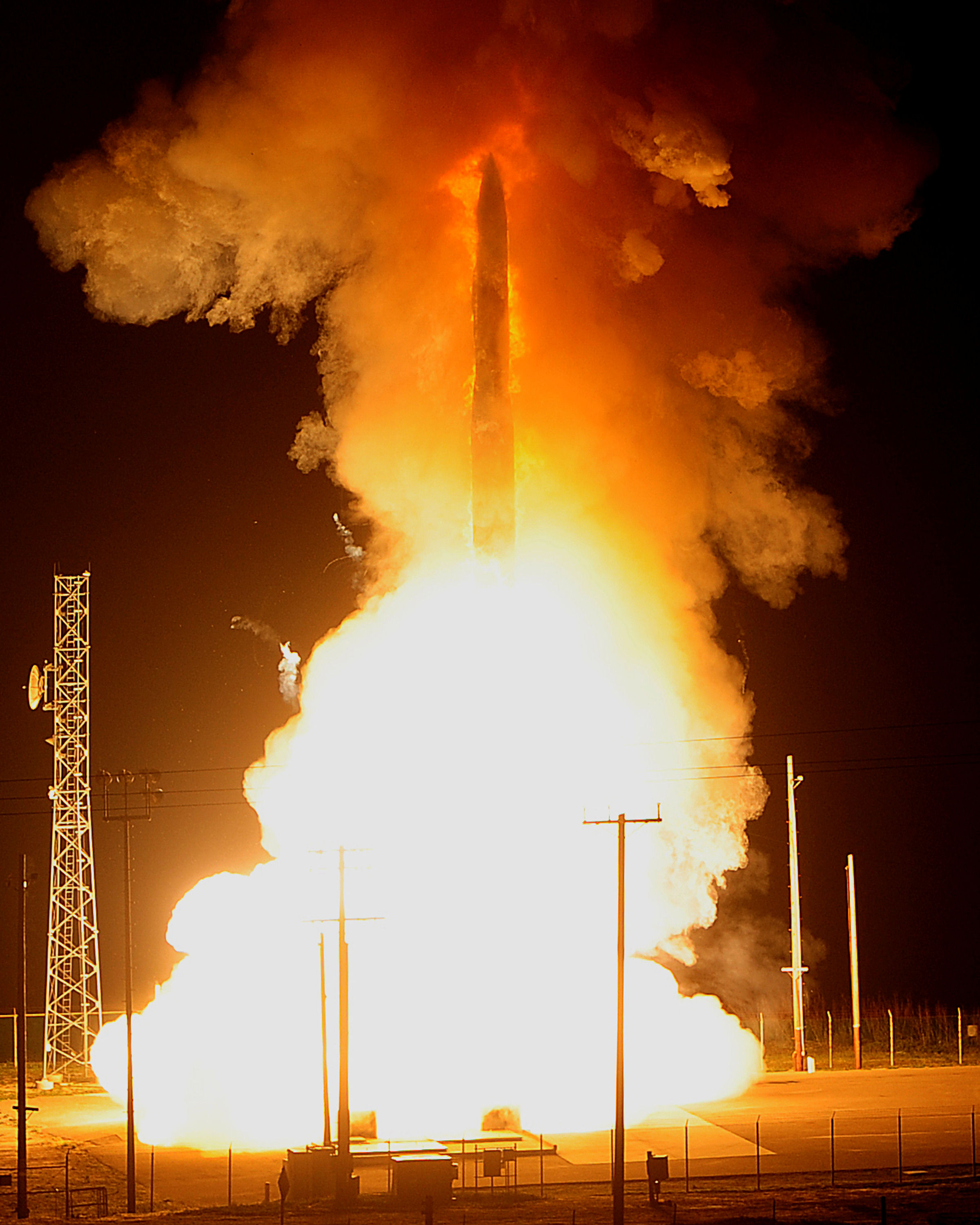 An unarmed Minuteman III rising from its silo during a test launch, shown in black and white